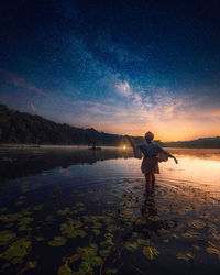 Rear view of man standing in lake against sky