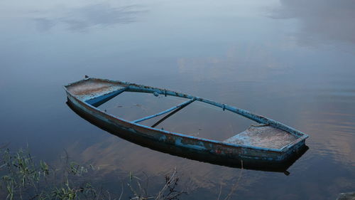 Abandoned boat moored in water against sky