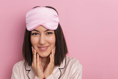 Portrait of young woman against pink background