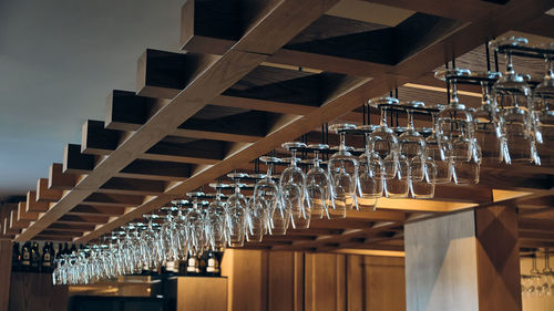 Lots of wine glasses hanging on a wooden rack above bar counter. empty glasses for wine in a winery