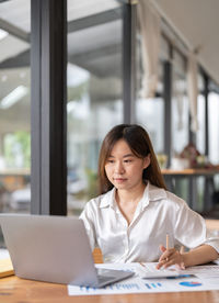 Portrait of smiling woman using laptop at table