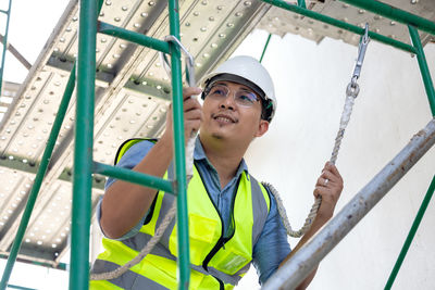 Low angle view of man working on ladder