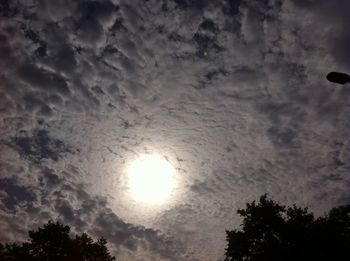 Low angle view of sun shining through clouds