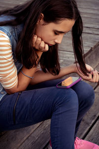 Side view of young woman sitting on hardwood floor