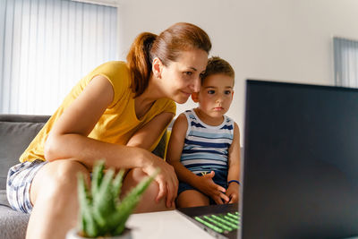 Mother and daughter sitting on mobile phone at home