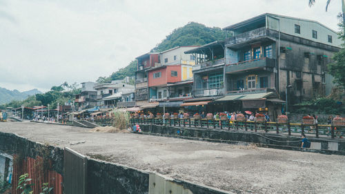 Buildings by road against sky in city