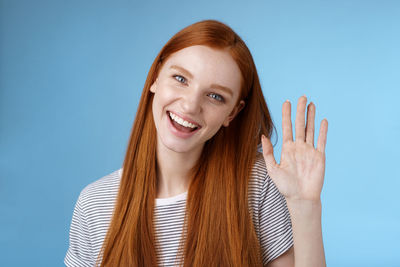 Smiling woman waving against blue background