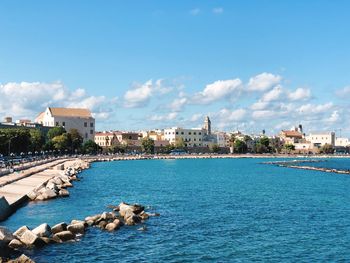 Buildings by sea against blue sky