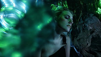 Woman with make-up relaxing by rocks in forest