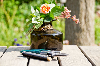 Close-up of flower vase with string and pruning shears on wooden table