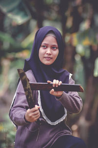 Portrait of young woman looking away while standing outdoors