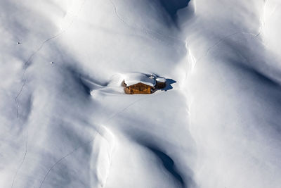 Aerial view of hut on snowcapped mountain against sky