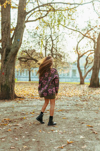Rear view of woman tossing hair while standing at park during autumn