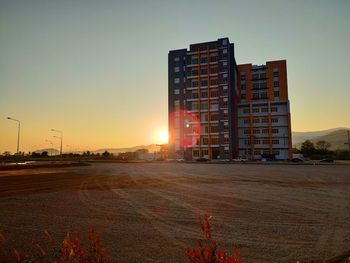 Road by building against sky during sunset