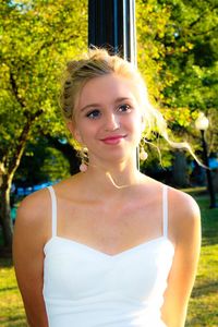 Portrait of smiling young woman against trees