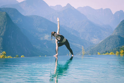 Woman exercising against lake and mountains