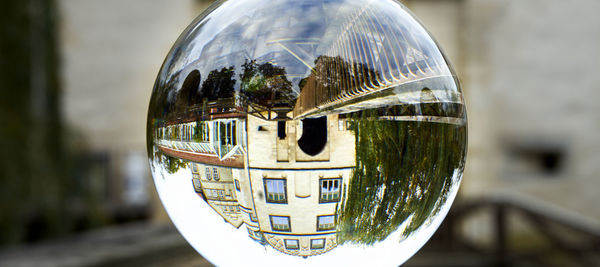 Close-up of crystal ball on glass against city