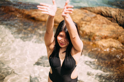 Portrait of young woman with arms raised