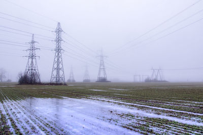 Electricity pylon on field against sky