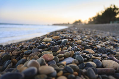 Close-up of pebbles at beach against sky during sunset
