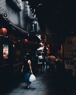 People walking on street by buildings in city at night