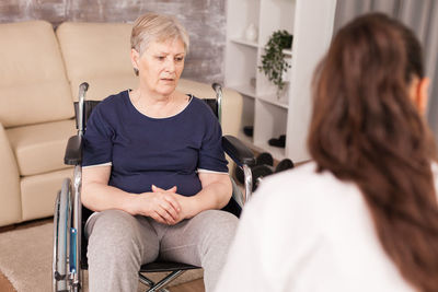 Disabled woman discussing with doctor at home
