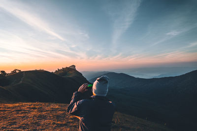 Rear view of man standing on mountain against sky