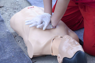 Midsection of paramedic performing cpr on mannequin