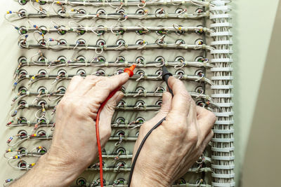 Cropped hands of electrician examining cables