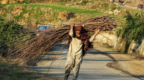 Man walking on footpath by road on field