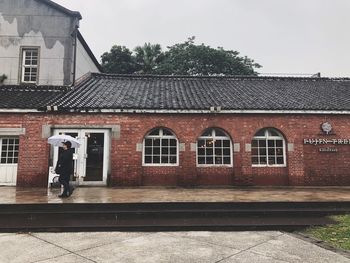 Man standing outside house against sky