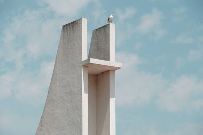 Low angle view of seagull perching on built structure against sky