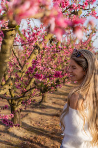 Portrait of young woman standing by tree