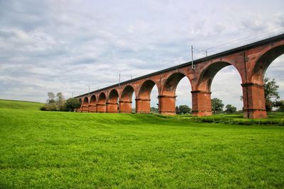 Bridge over field against sky