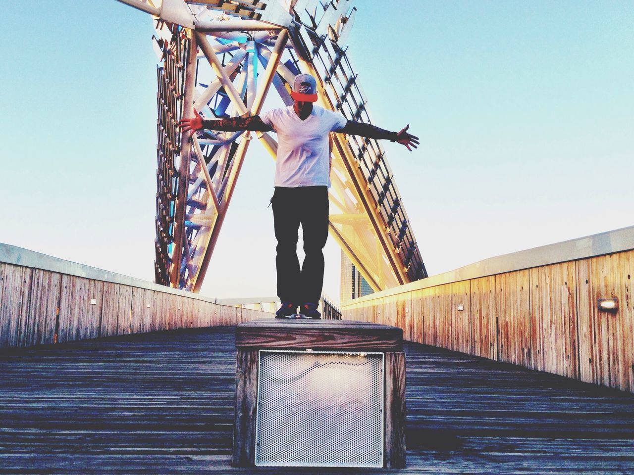 clear sky, lifestyles, full length, leisure activity, built structure, low angle view, blue, architecture, railing, casual clothing, standing, men, rear view, copy space, connection, bridge - man made structure, day, person