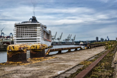 Mooring bollard at harbor against cloudy sky in city