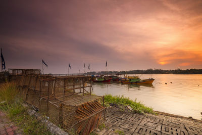 Boats moored in sea against sky during sunset