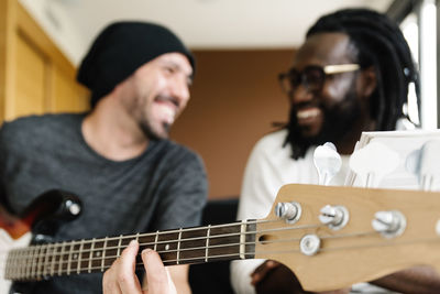 Smiling man playing guitar by friend