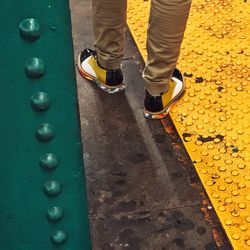 Low section of man standing on yellow shoes