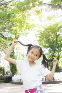 Portrait of smiling girl standing against trees