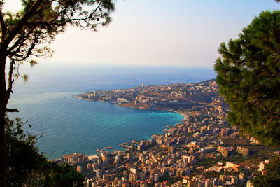 Aerial view of townscape by sea against sky