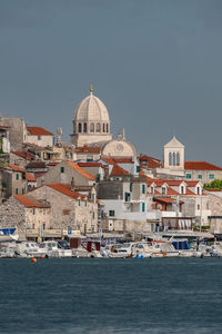 Buildings by sea against clear sky