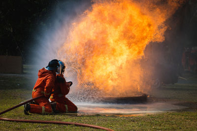 Firefighters spraying water on fire with hose