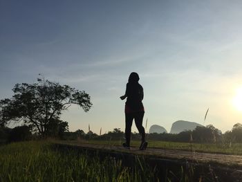 Full length of woman jogging on footpath against sky during sunset