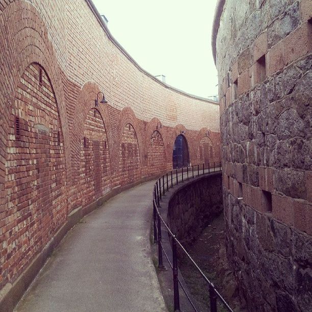 architecture, built structure, arch, the way forward, connection, building exterior, history, bridge - man made structure, indoors, railing, diminishing perspective, travel destinations, brick wall, transportation, stone wall, famous place, archway, clear sky, travel, arch bridge