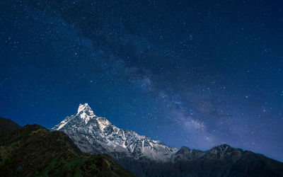 Scenic view of snowcapped mountains against sky at night