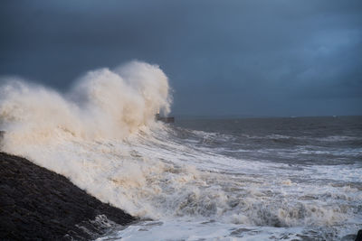 Scenic view of splashing waters in sea against sky