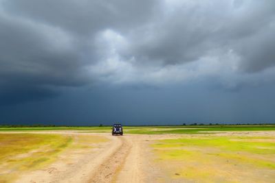 Tire tracks on agricultural field against storm clouds