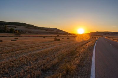 A empty road crossing agricultural field at sunset