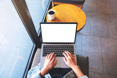 Top view mockup image of a woman using and typing on laptop computer with blank white desktop screen